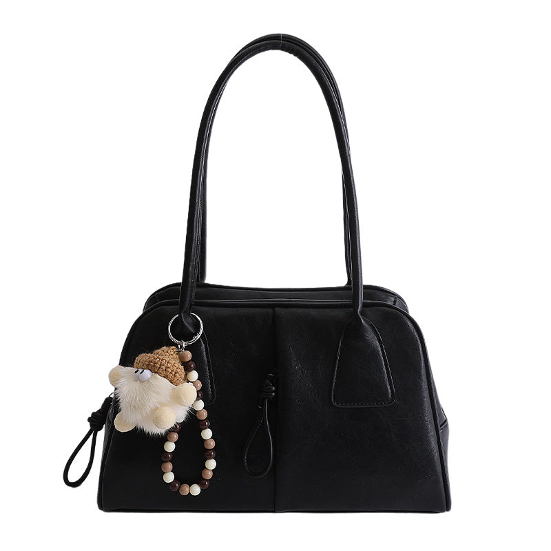 Black handbag with a keychain featuring a plush toy on a white background
