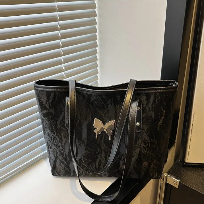 Black textured totebags with a butterfly design on a surface near blinds