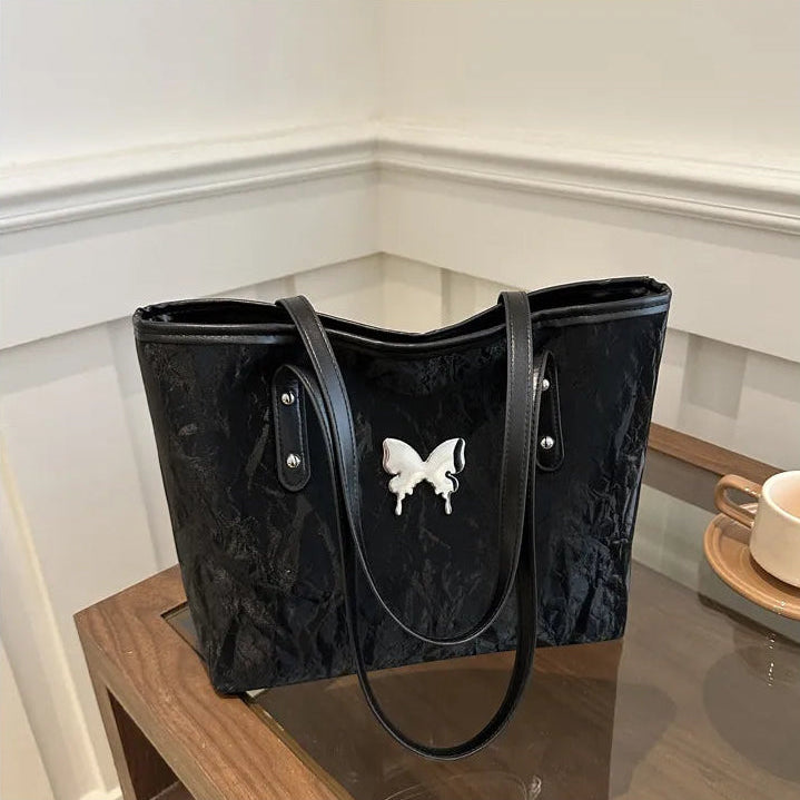 Black textured totebag with a butterfly design on a reflective surface.