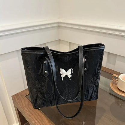 Black textured totebag with a butterfly design on a reflective surface.