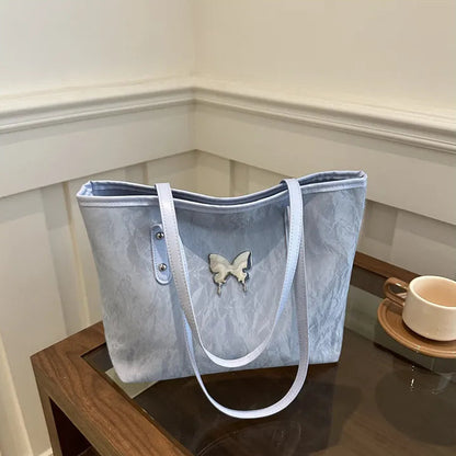 Light blue tote bag with a butterfly design on a wooden table.