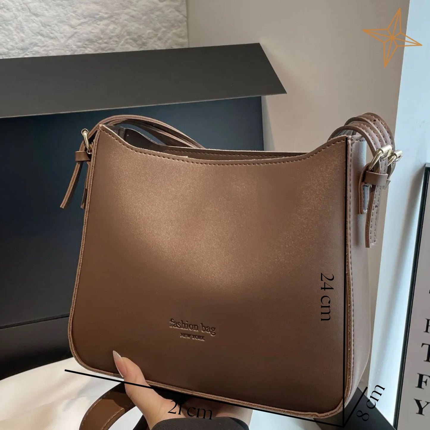 Brown handbag with measurements held by a hand, against a neutral background.