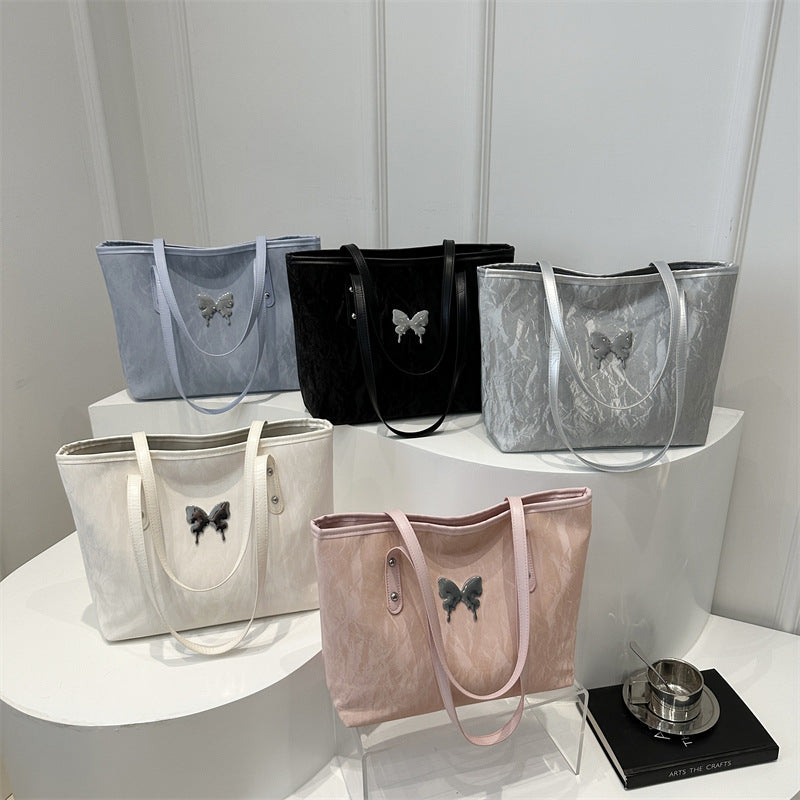 Collection of totebags with butterfly designs on a white surface against a light gray background