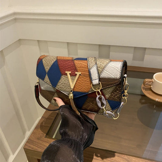 Multicolored patchwork handbag held by a person in a room with a coffee cup on a table.