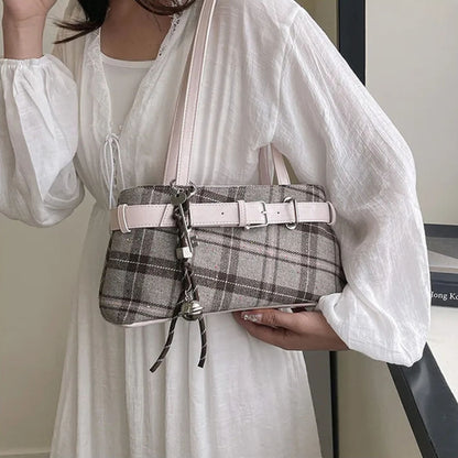 Person holding a plaid shoulder bag with plaid pattern with a white outfit