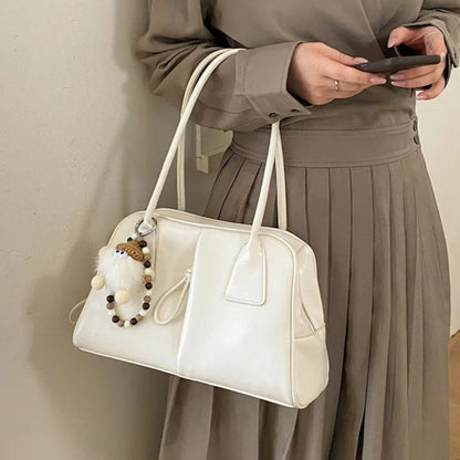 Person holding a white handbag with decorative elements against a neutral background