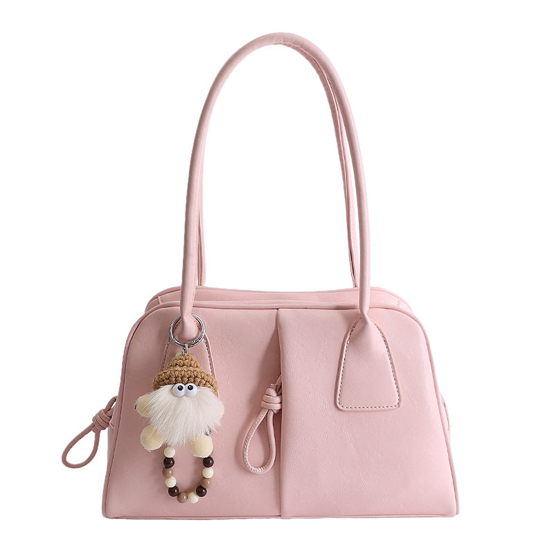 Pink handbag with a fluffy keychain on a white background