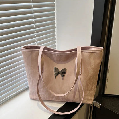 Pink tote bag with butterfly design on a surface near a window with blinds.