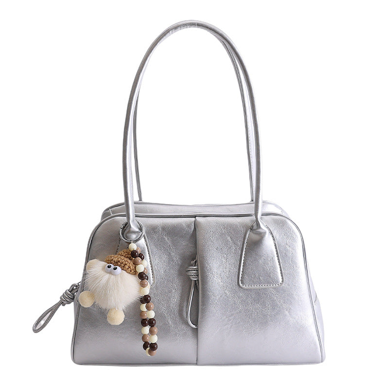 Silver handbag with a fluffy keychain on a white background