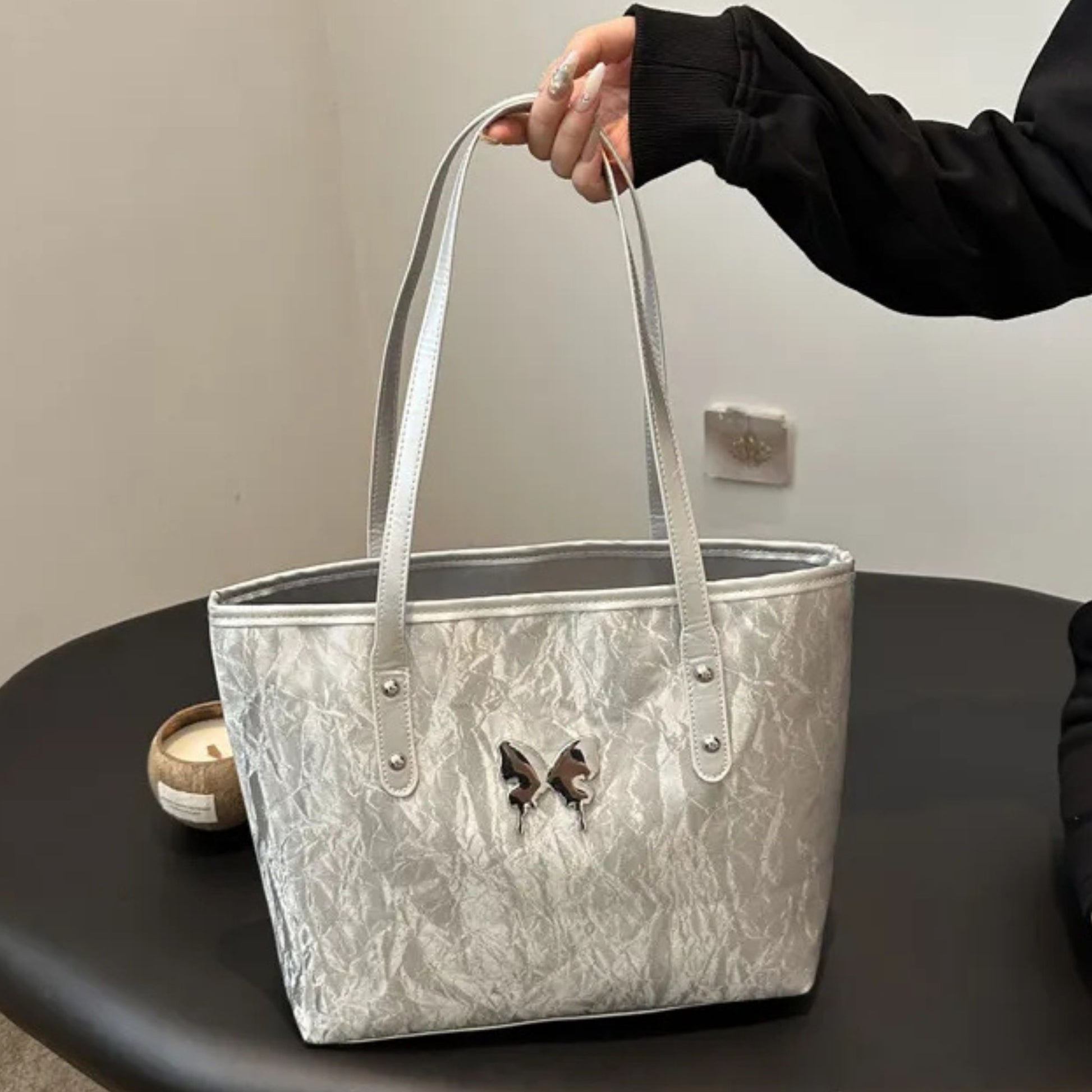 Silver marbled totebag held by a person on a dark surface with a neutral background