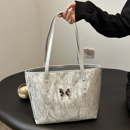 Silver marbled totebag held by a person on a dark surface with a neutral background