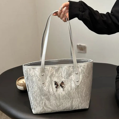 Silver marbled totebag held by a person on a dark surface with a neutral background