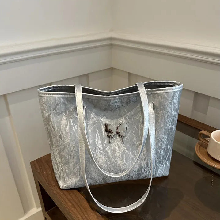 Silver textured tote bag on a wooden surface with a neutral background