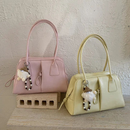 Two handbags, one pink and one yellow, with keychains on a textured surface.