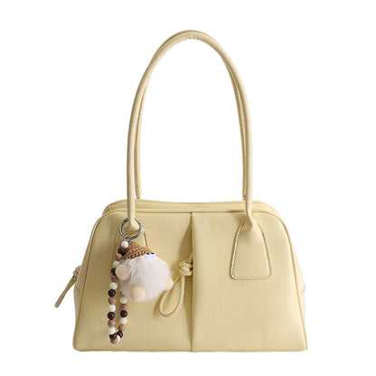 Yellow handbag with a decorative keychain on a white background