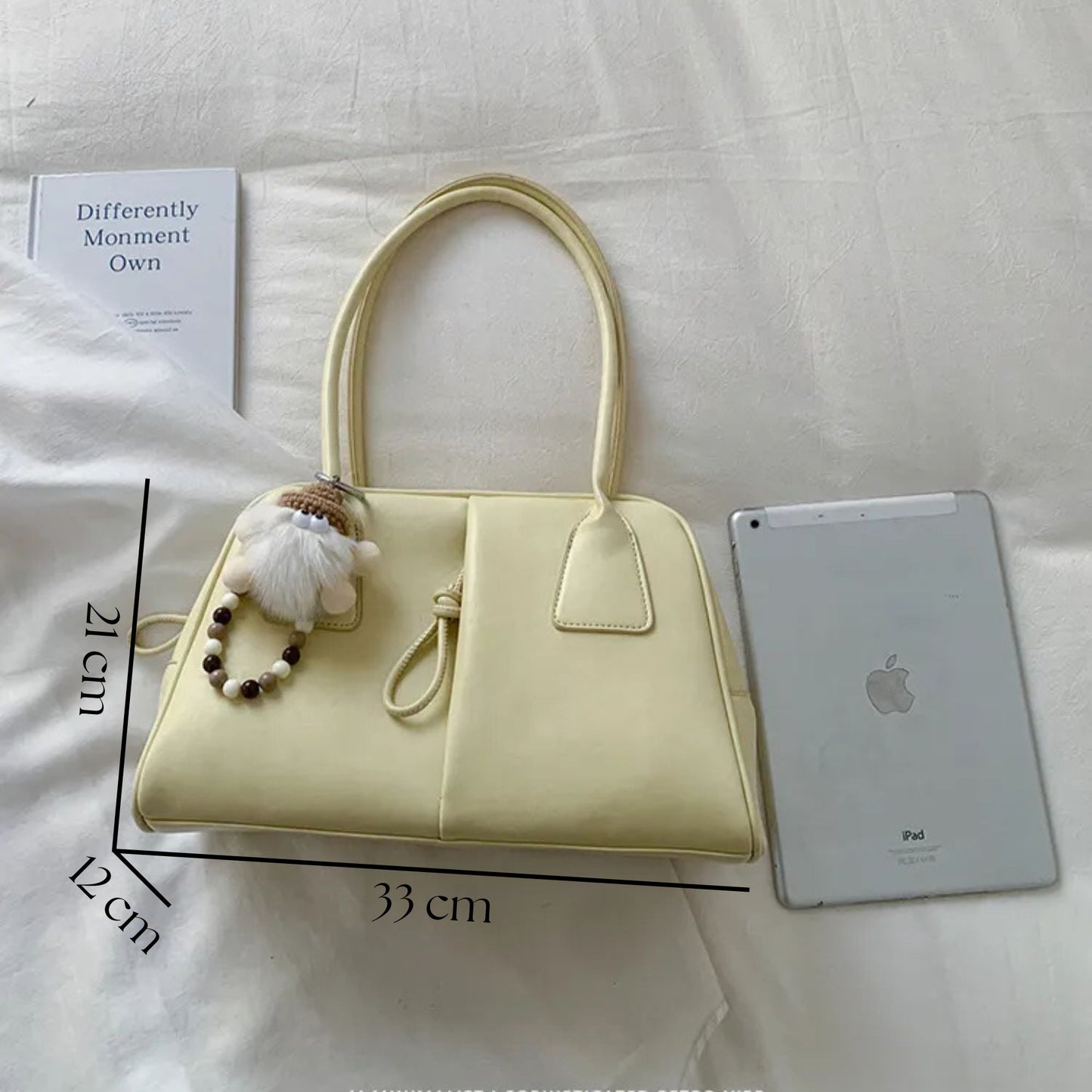 Yellow handbag with measurements, a small plush toy, and an iPad on a light background