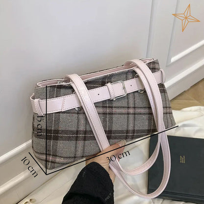 Plaid shoulder bag with pink straps held by a person, with measurements indicated.