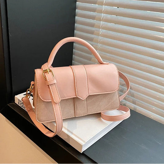 Pink crossbody bag on a book with blinds in the background